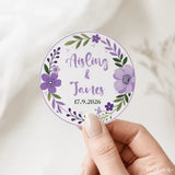 A circular purple and green floral wreath wedding favor sticker with aisling and james real foil colors date 17.9.2026