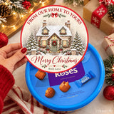 A festive blue chocolate tub featuring a snow-dusted cottage lid perfect for christmas gifts from cadbury roses