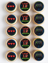 Gaming birthday cupcake toppers with pixelated level 12 unlocked text and black game controllers on dark backgrounds