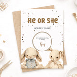 Gender reveal card with two bunnies and text 'He or She' on a white background.