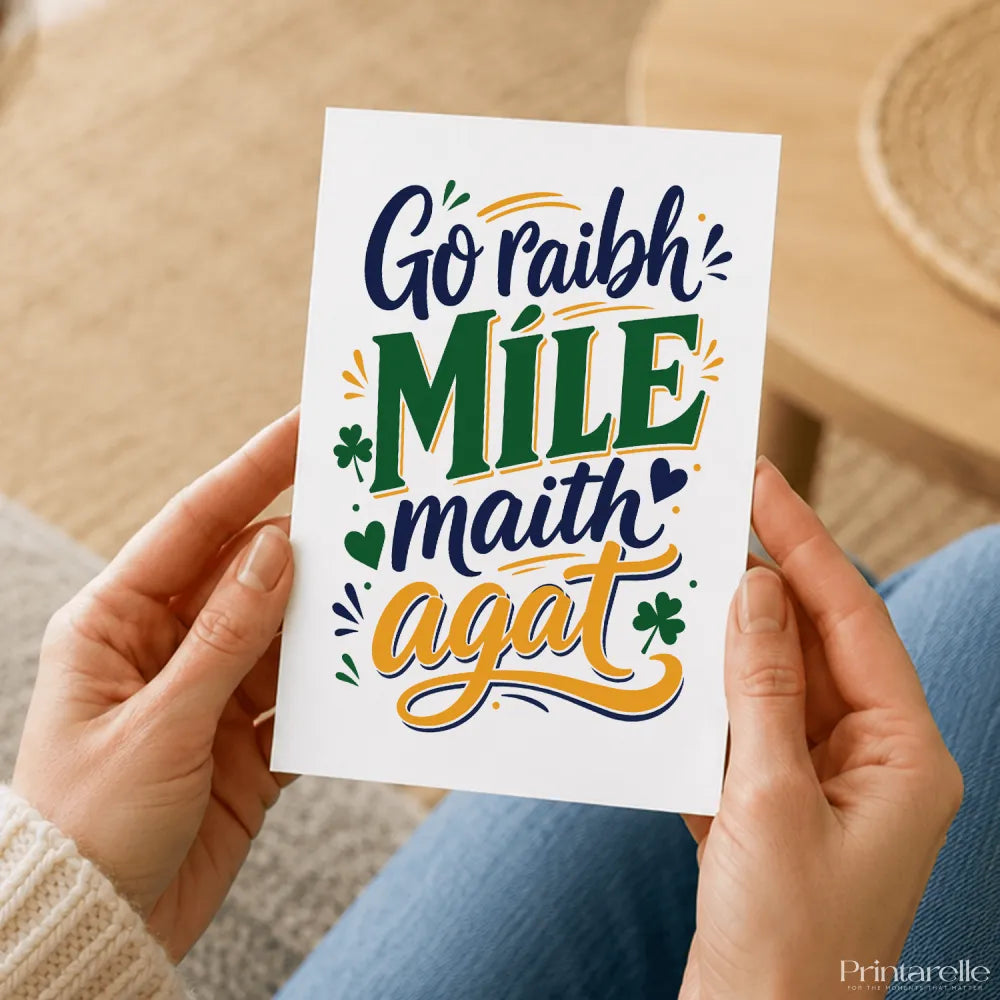 A white thank you card with navy blue green and gold míle maith agat lettering and shamrock accents