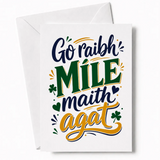 A white thank you card with navy blue green and gold lettering saying go raibh míle maith agat with shamrock accents