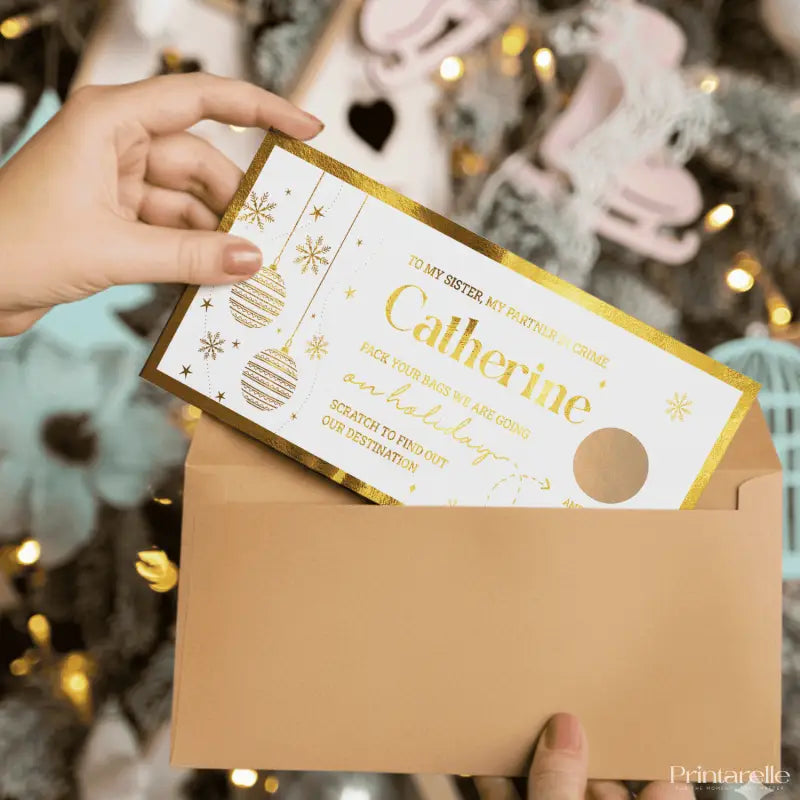 Hand holding a Christmas-themed gift card with an envelope against a festive background.