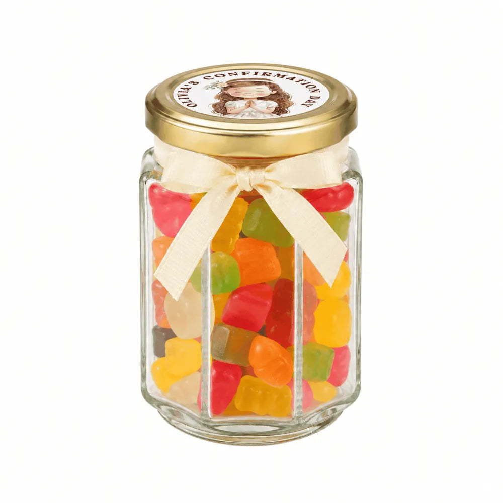 A clear glass hex jar filled with gummy bears, featuring a 48mm pale gold lid and personalised sticker printed bow for halo grace confirmation