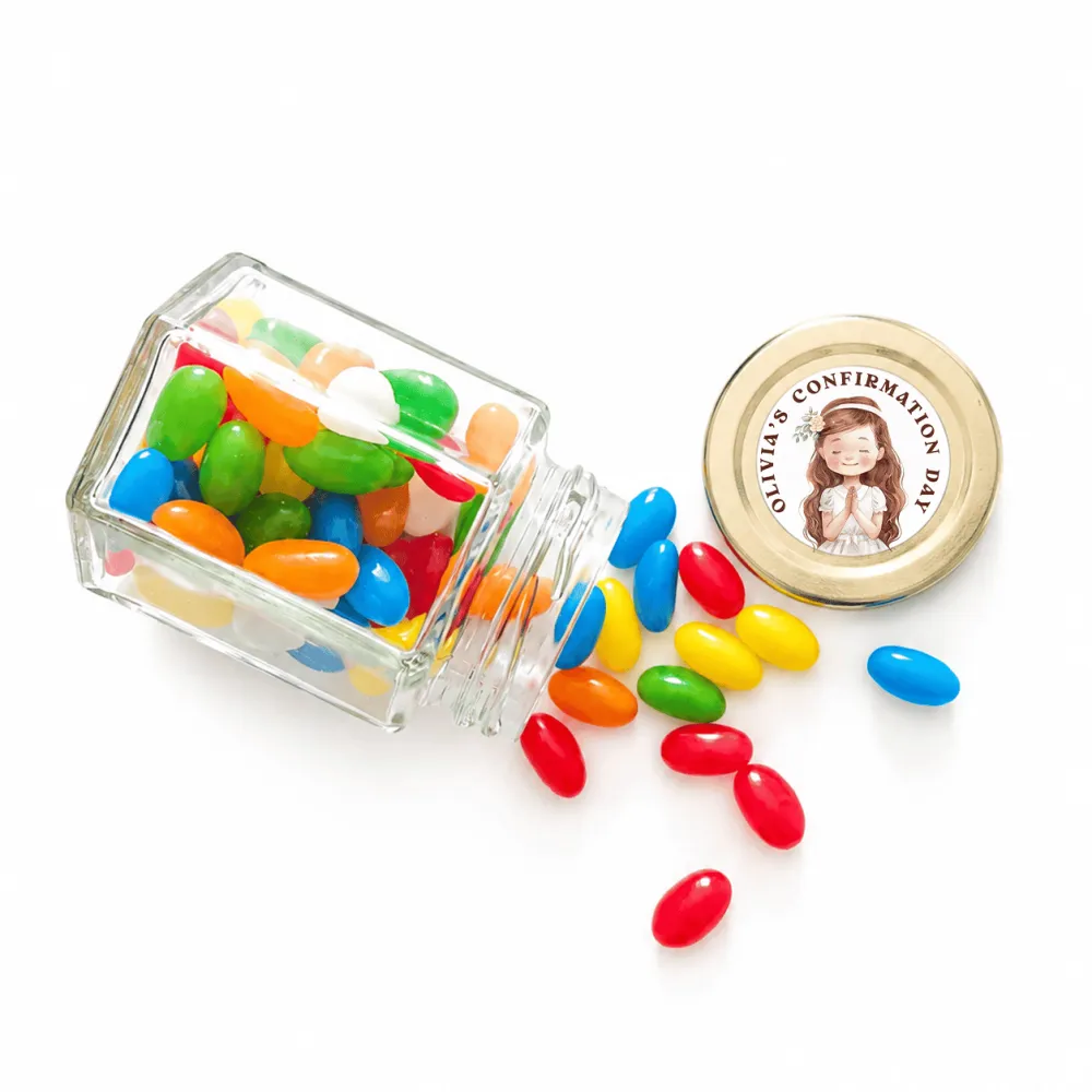 A clear glass hex jar tipped over spilling colorful jelly beans with a 48mm pale gold twist lid and personalised sticker printed halo grace confirmation favor