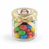 A clear glass personalised mini jar favour with 43mm pale gold twist lid and colourful candy for halo grace confirmation
