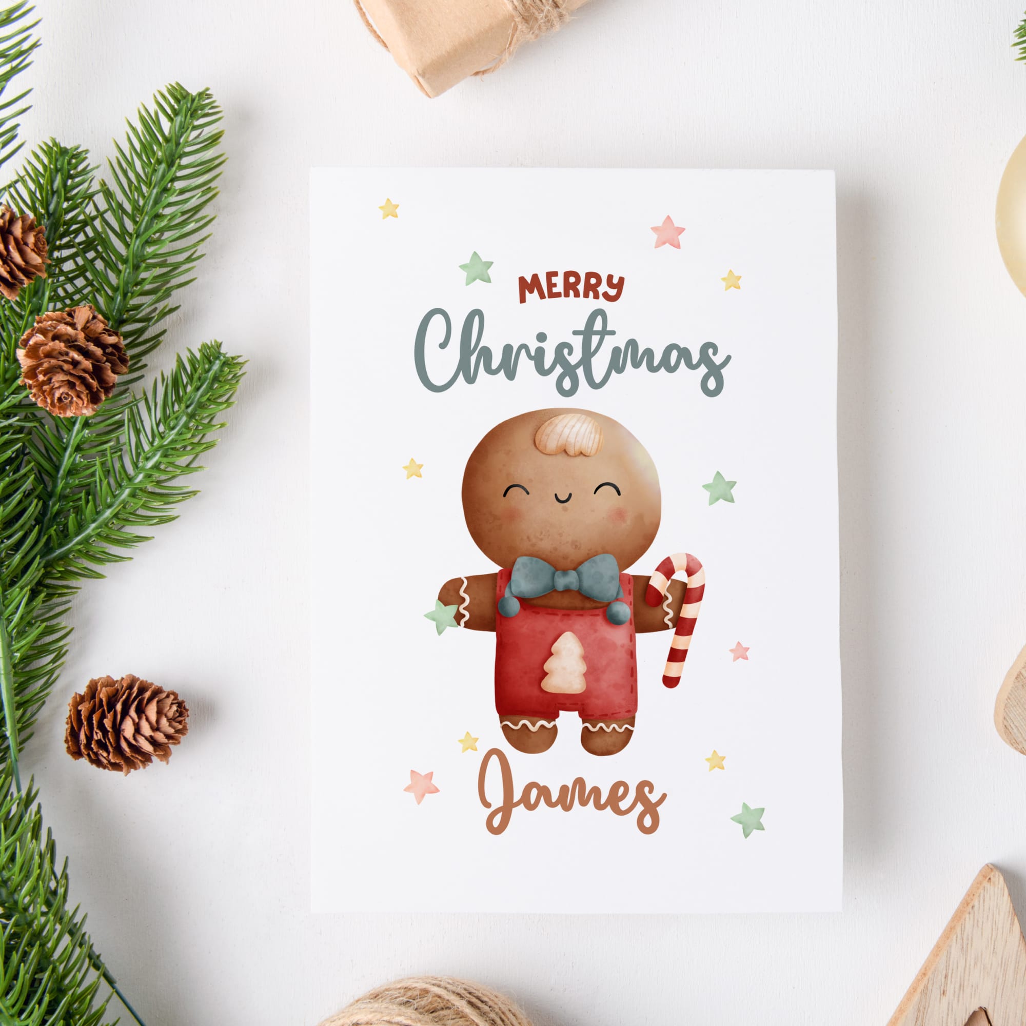 Christmas card with a gingerbread man design and 'Merry Christmas James' text, surrounded by festive elements on a white background.