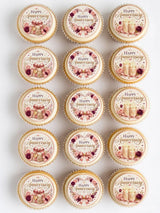 Delicate round anniversary cupcake toppers with pink rose gold floral designs and bows on cream cupcakes in a gift box