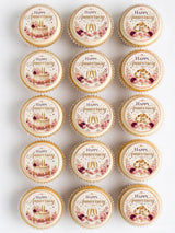 Delicate round edible cupcake toppers with happy anniversary script pink roses and gold rings on cream icing sheet