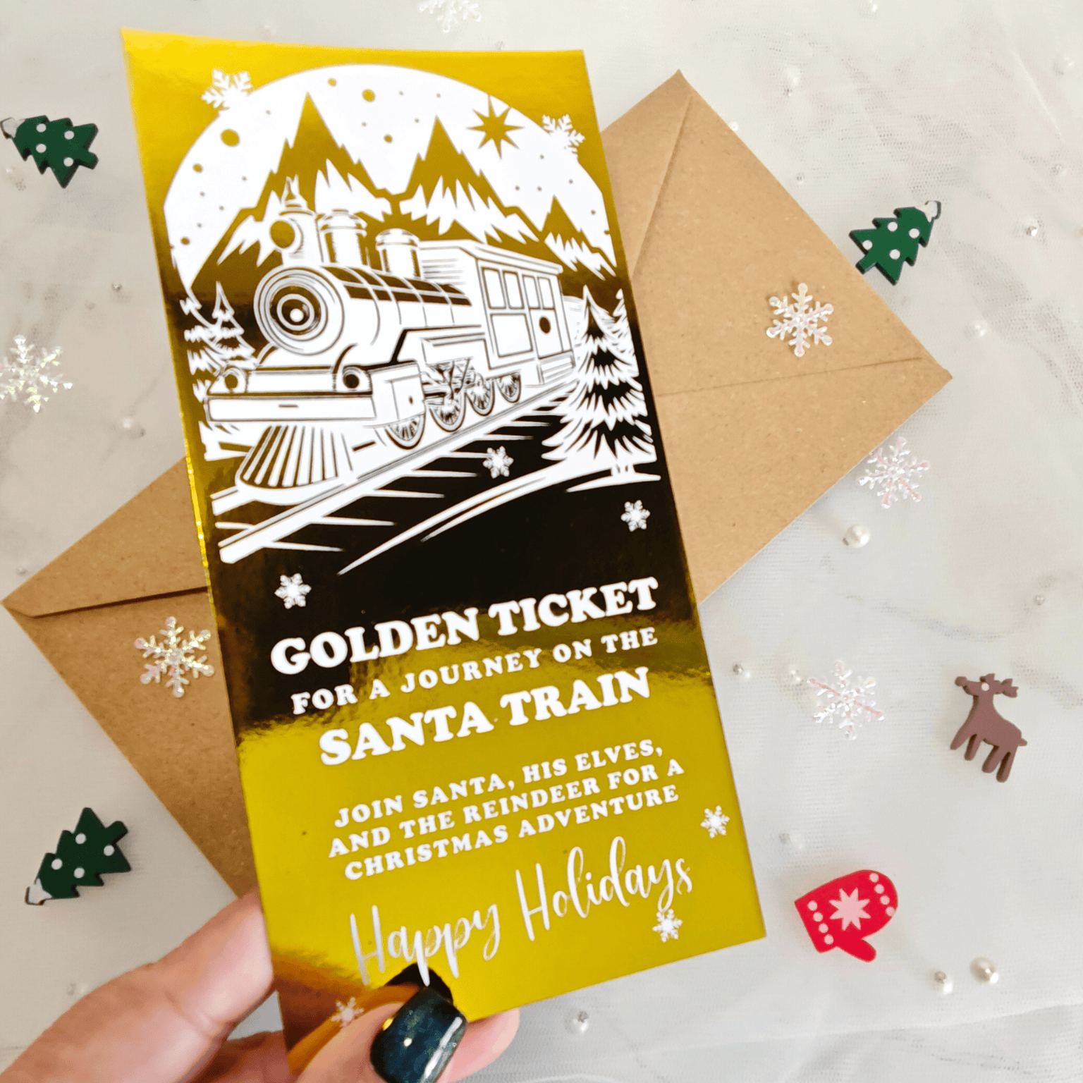 Holiday-themed invitation card with a Santa train design on a yellow background, held by a hand.