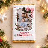 A white chocolate bar with gold foil edges featuring a christmas photo framed by green holly and a pink bow holly photo frame gift wrap