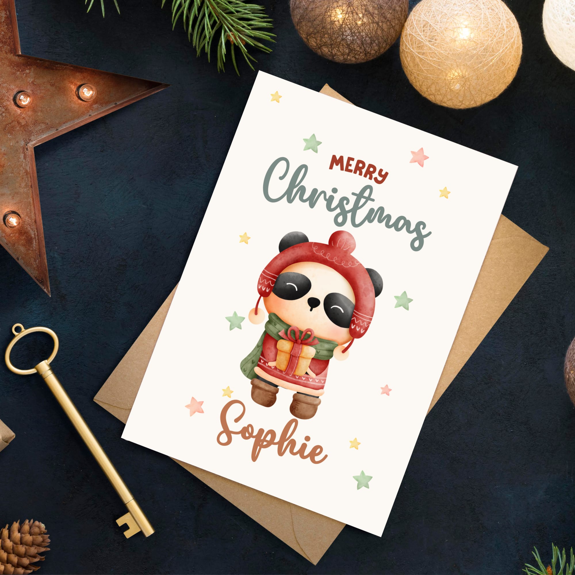 Christmas card with a panda character and 'Merry Christmas Sophie' text, surrounded by festive decorations on a dark surface.