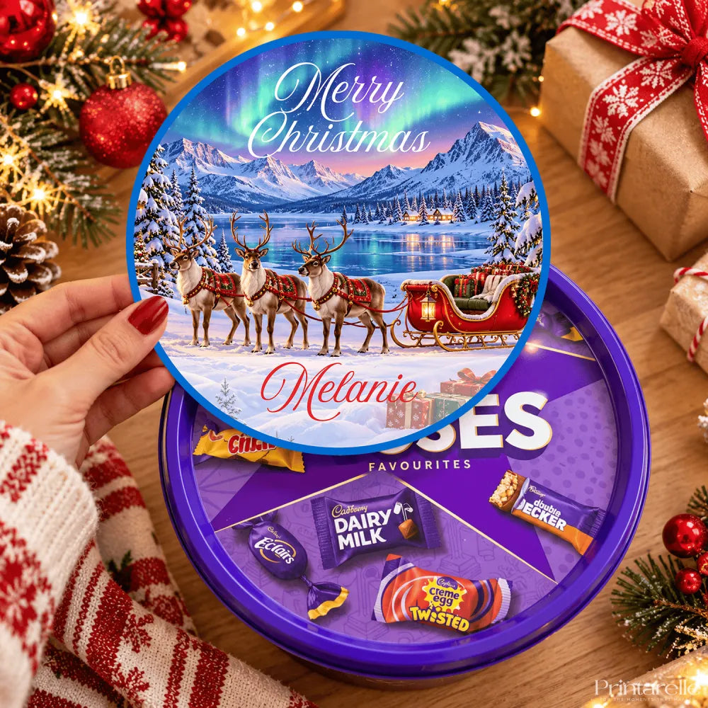 Purple circular cadbury chocolate tin with festive merry christmas tub sticker showing reindeer sleigh northern lights frozen lake
