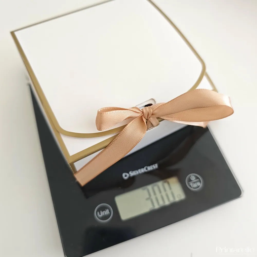 A white and gold late late toy show sweet box with a delicate rose gold satin ribbon bow for christmas treats