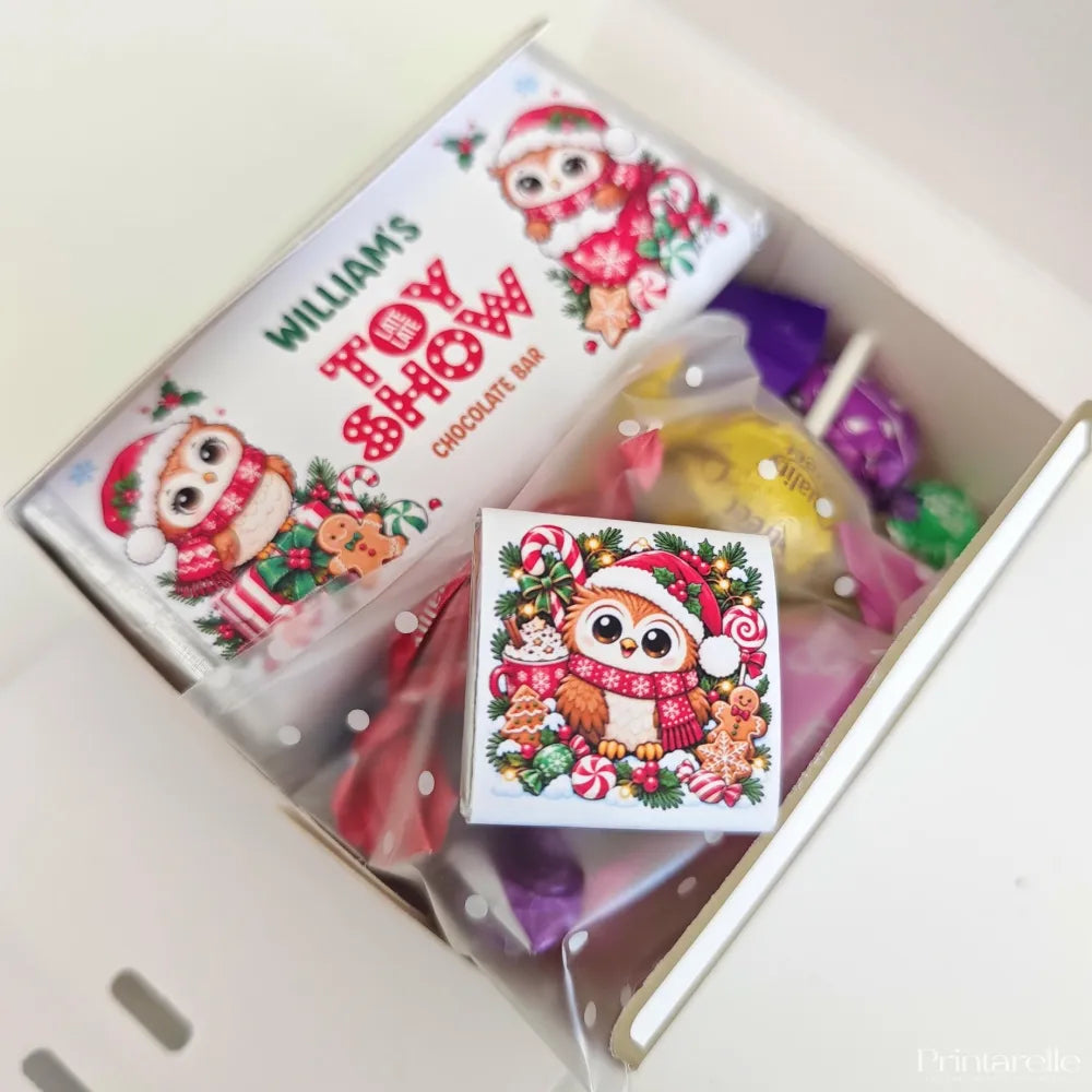 A festive white chocolate late late toy bar with a cartoon owl santa surrounded by holiday treats