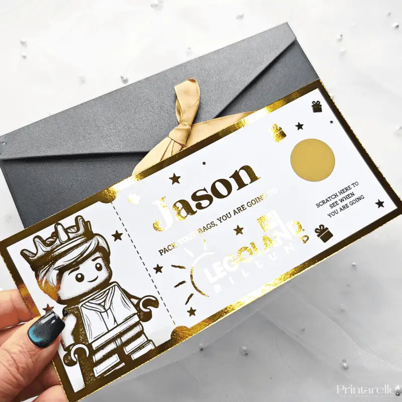 Gift card with gold and white design held by a hand, with a gray envelope in the background.