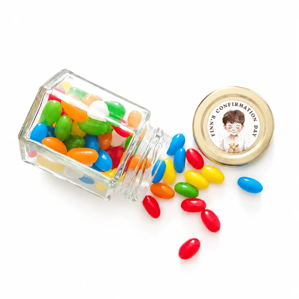 A clear glass personalised hex jar favour tipped over spilling colorful jelly beans with a 48mm pale gold twist lid