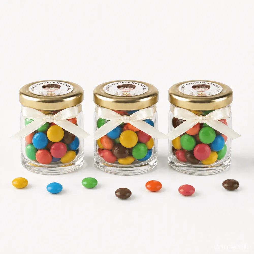 Three clear glass jars with 43mm pale gold lids and white ribbons filled with colourful m&m’s for little believer confirmation