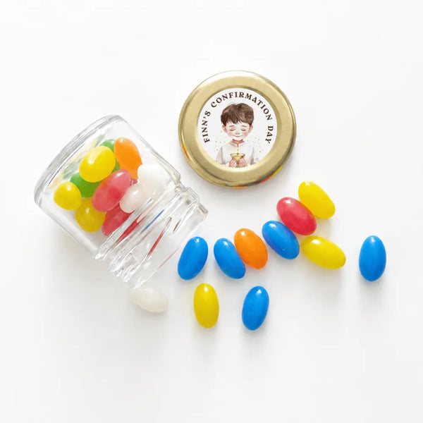 A clear glass jar with a 43mm pale gold twist lid and a personalised sticker for finn’s confirmation day filled with jelly beans