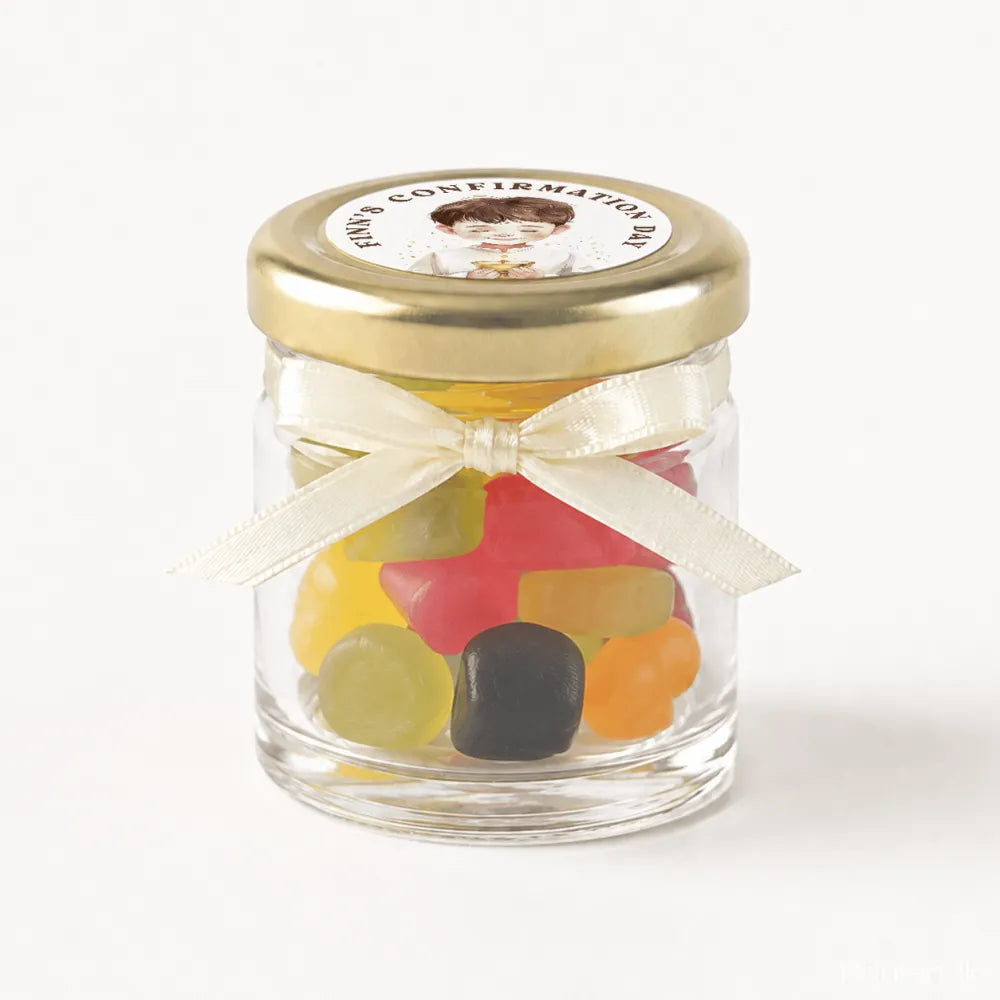 A clear glass mini jar favour with a 43mm pale gold lid, ivory ribbon bow, and colourful gummy candies inside