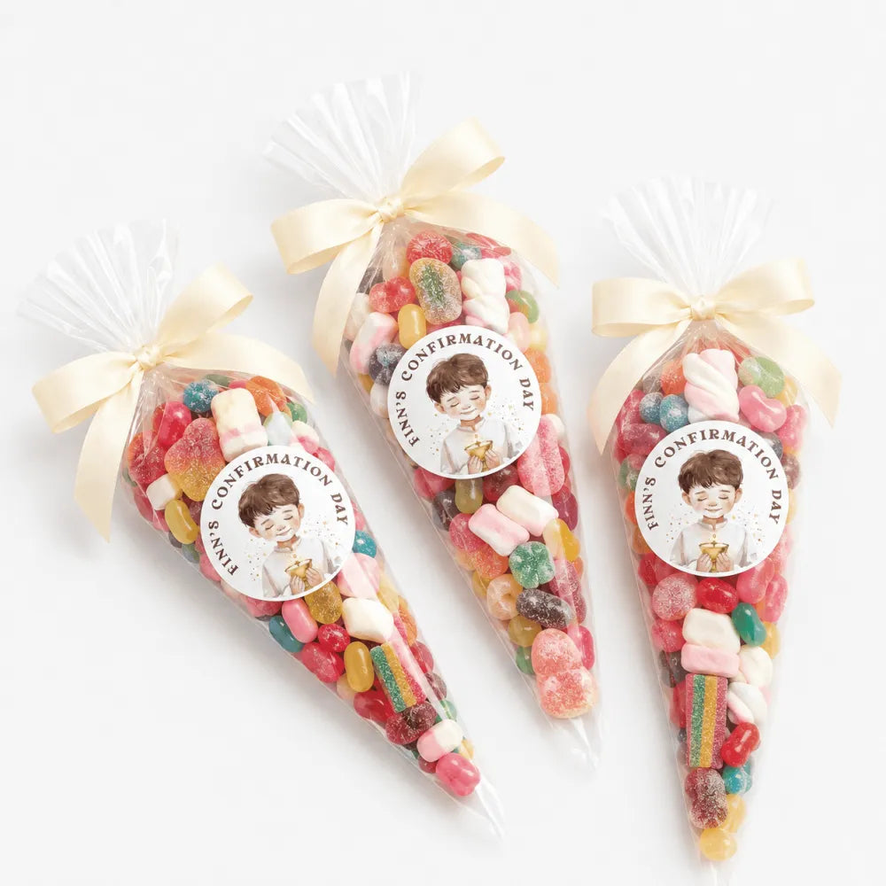Three clear plastic sweet cones tied with cream ribbons and boy labels for finn’s confirmation day filled with gummies