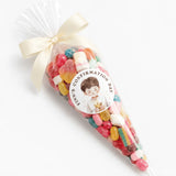 A clear plastic sweet cone filled with colorful gummies tied with cream ribbon and labelled for finn’s confirmation day