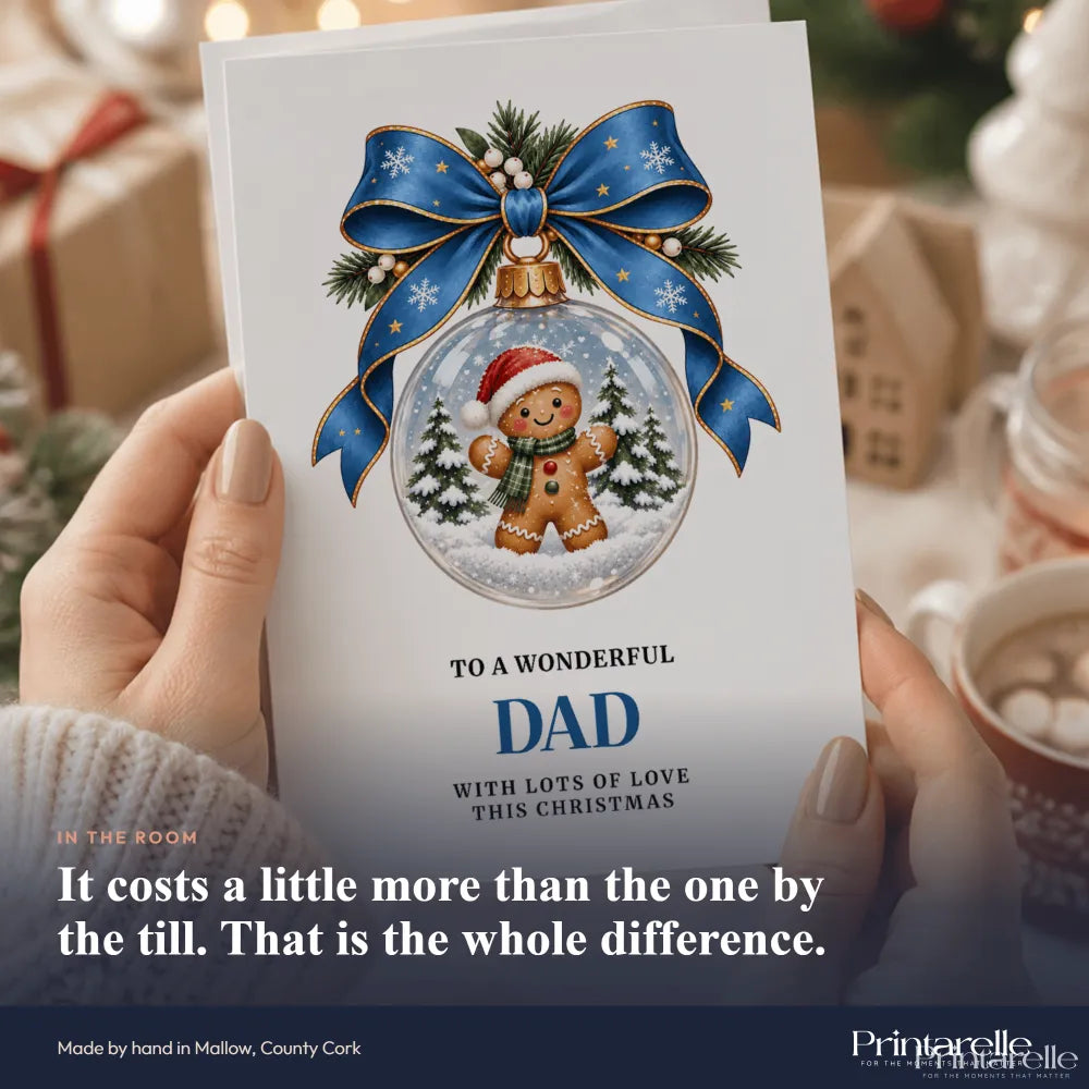 A festive white dad christmas card featuring a gingerbread dad inside a glass bauble with pine sprigs and a blue bow