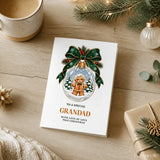 White christmas card featuring a gingerbread grandad with round glasses and bow tie inside a snow globe with green ribbon