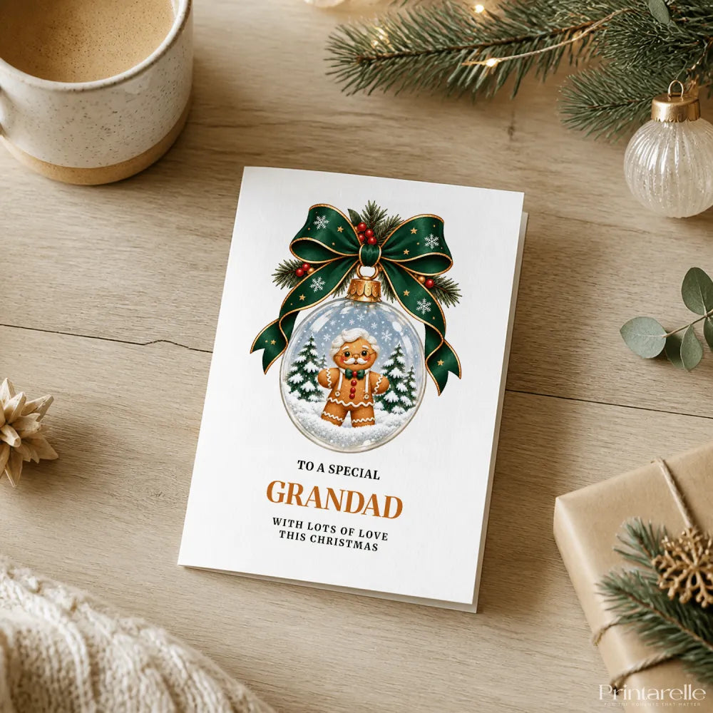 White christmas card featuring a gingerbread grandad with round glasses and bow tie inside a snow globe with green ribbon