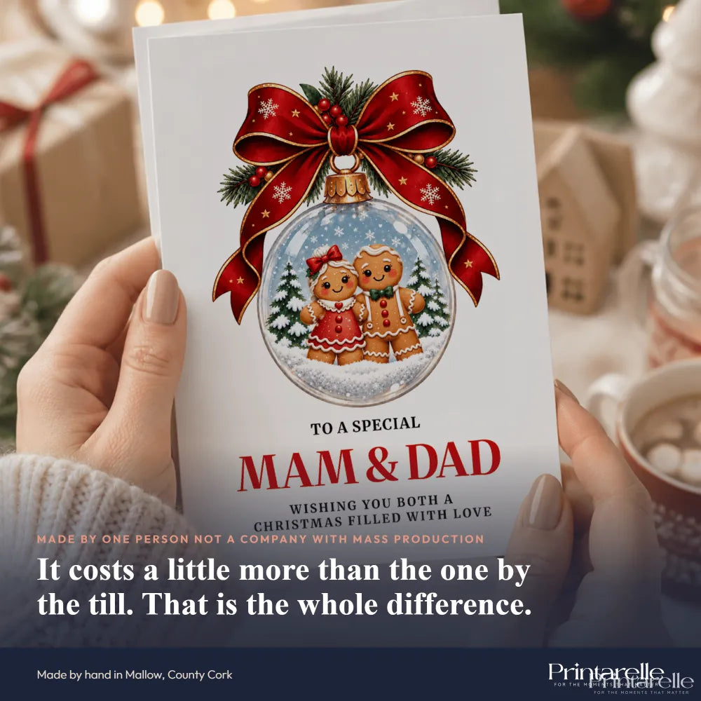 A festive white dad christmas card featuring a gingerbread couple inside a glass ornament with a red ribbon bow