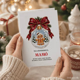 White christmas card featuring a gingerbread man in a snow globe with red bow and pine sprigs mamó christmas card