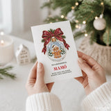A white mamó christmas card featuring a gingerbread man snow globe with red ribbon and pine sprigs, perfect for christmas