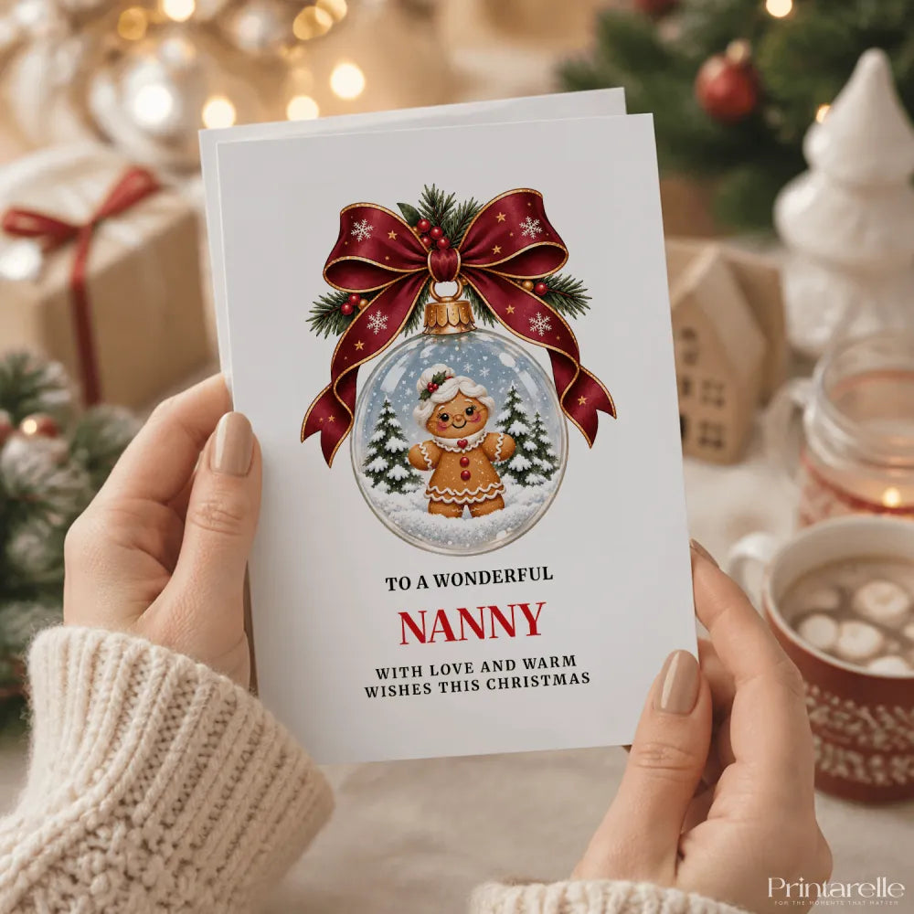 White nanny christmas card featuring a gingerbread nanny in a snow globe with pine trees and a red ribbon bow
