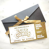 Gold ticket-style invitation with a black envelope and gold ribbon on a white background