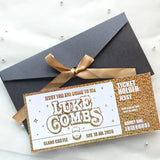 Concert ticket with gold and white design on a black envelope with a gold ribbon.