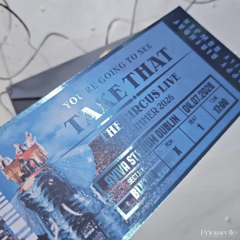 Blue concert ticket for 'Take That' with event details on a textured surface