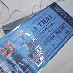 Blue concert ticket for 'Take That' with event details on a textured surface