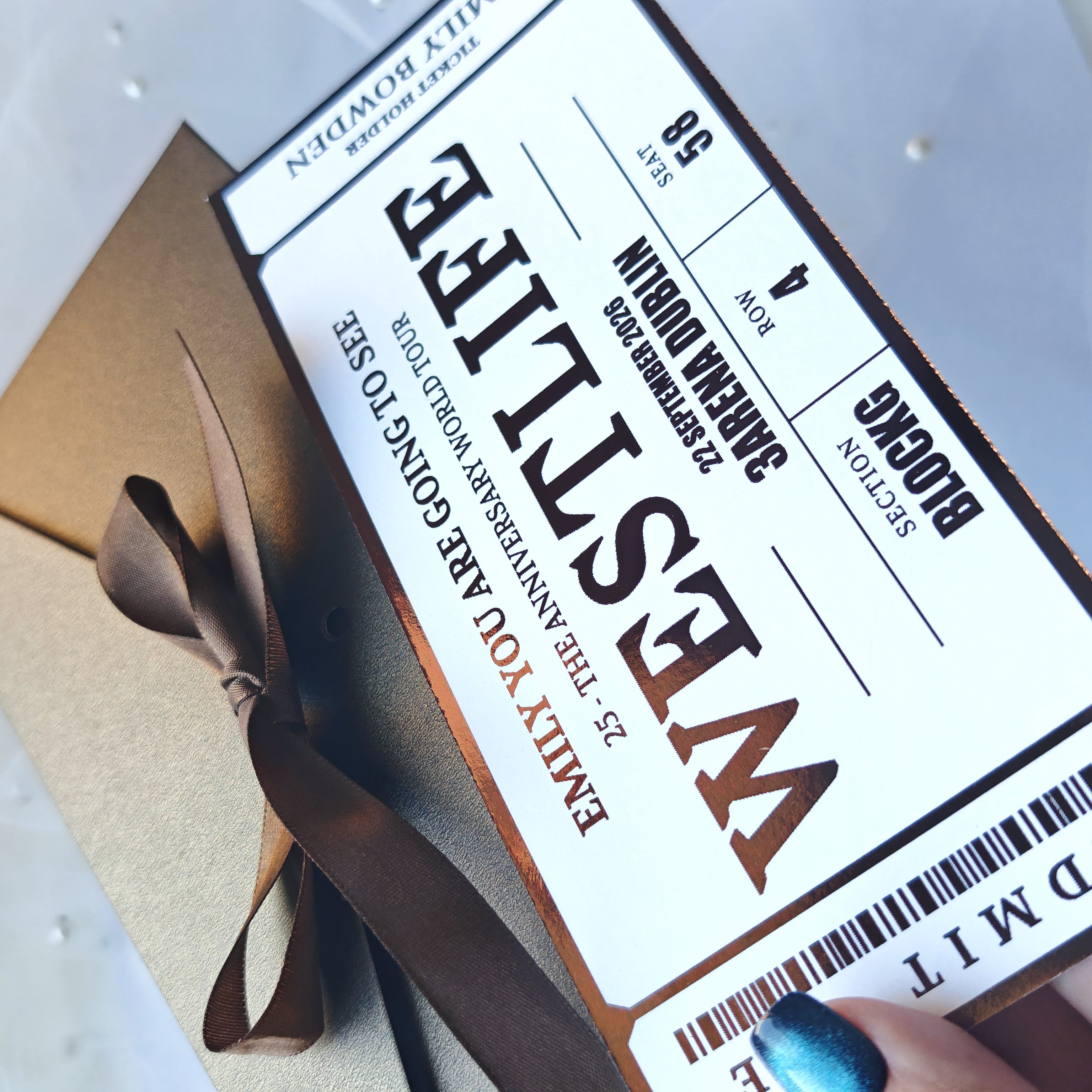 Ticket-like design with text and a brown ribbon on a light background