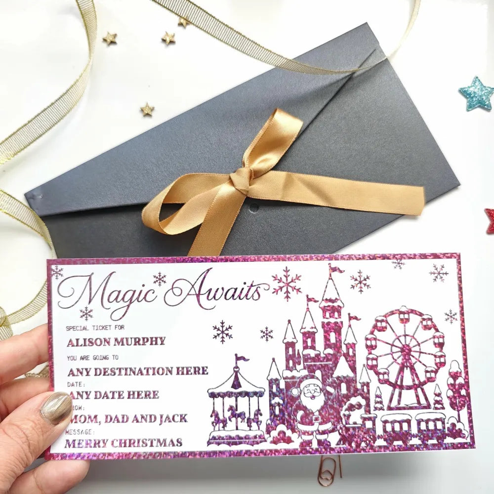 A festive pink glitter reveal card featuring a whimsical winter theme park with santa castles and a ferris wheel