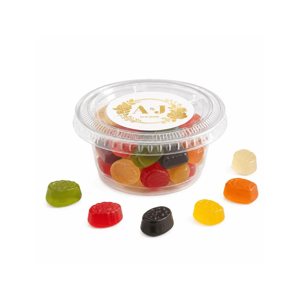 Clear plastic mini tub with gold and white monogram wreath foiled lid holding assorted colorful gummy candies