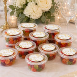 Clear plastic mini tub filled with colorful gummy candies sealed with white gold monogram wreath foiled lid r&k