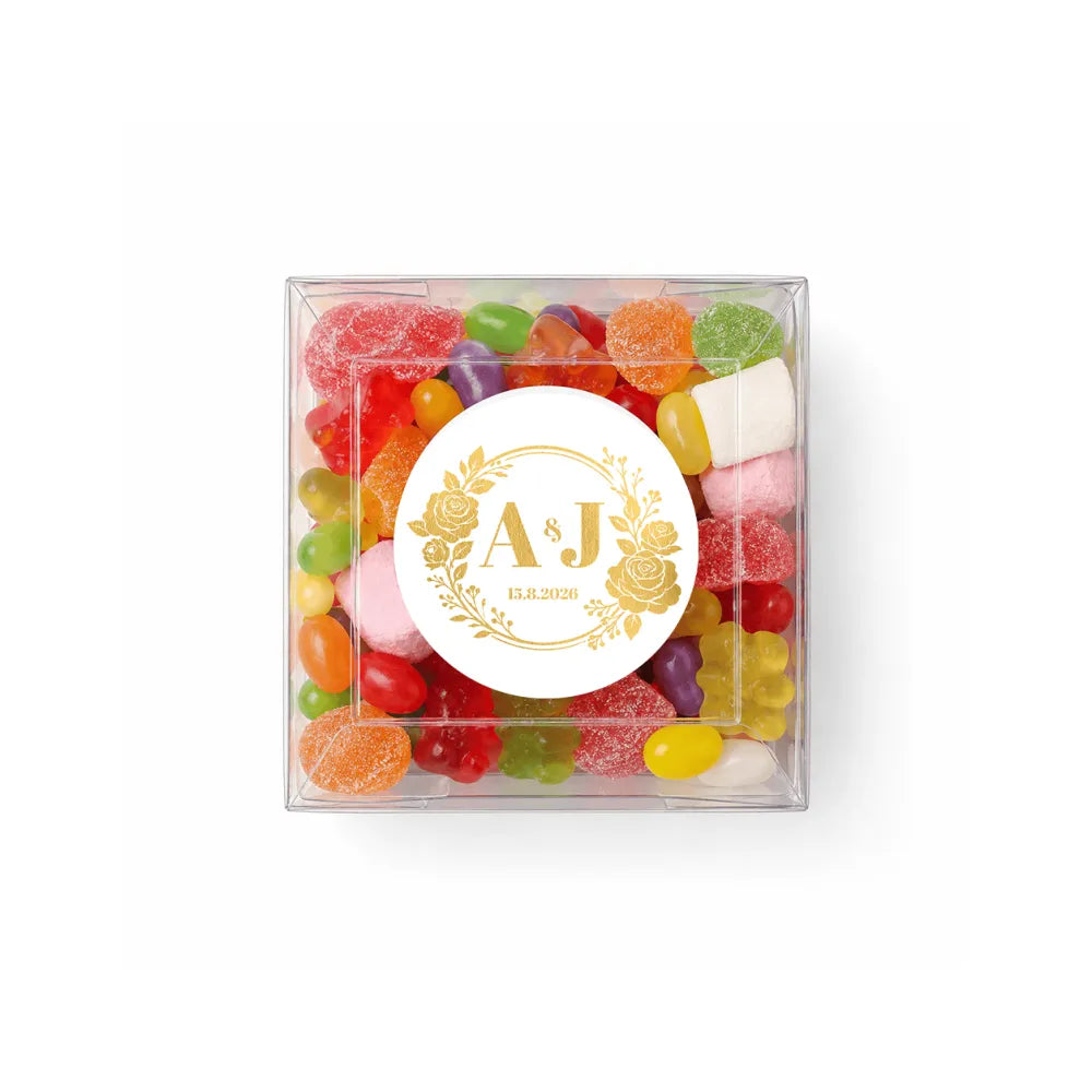 Clear box filled with colorful gummy candies and marshmallows with a monogram wreath foil sticker for wedding date