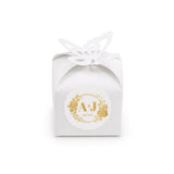 White paper favour box with gold foil monogram wreath stamp and butterfly cutout for wedding favours