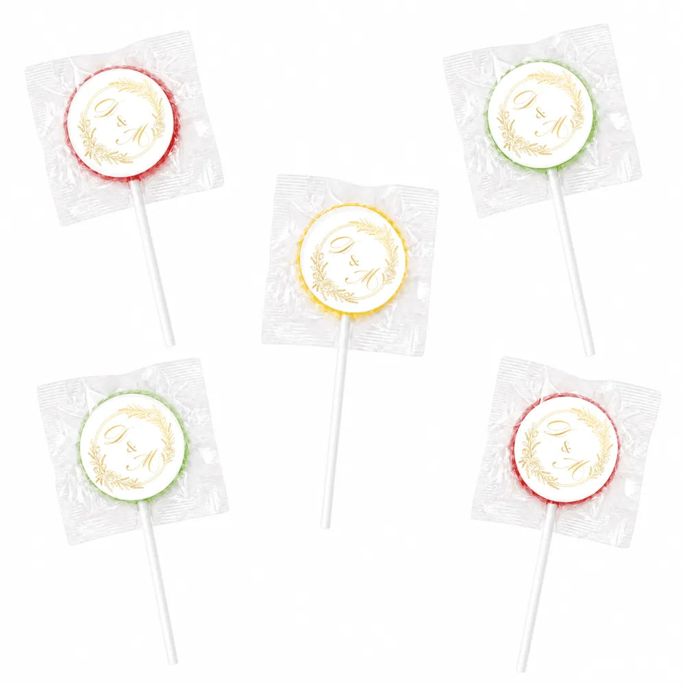 Round colorful lollipops with white centers and gold monogram wreath foil stickers wrapped in clear cellophane wedding favours