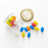 Clear glass monogram wreath mini jar wedding favours with gold lids ribbon bow and colorful candy inside