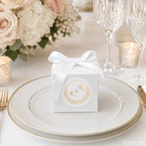 White cube favour box with gold monogram wreath foil sticker and satin ribbon bow for weddings