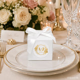 White cube favour box with gold foil monogram wreath design tied with satin ribbon bow for wedding gifts