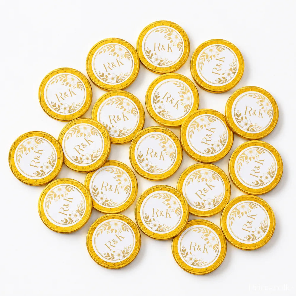Golden 40mm milk chocolate coins with white centers and r and k monogram surrounded by floral wreaths for wedding favours