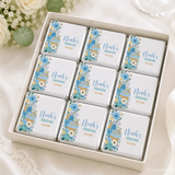 Nine mini neapolitan chocolates in a white box with blue and green floral moses basket baby carriage design