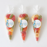 Three clear plastic sweet cones filled with colorful gummies and blue noah’s christening labels for moses basket gift